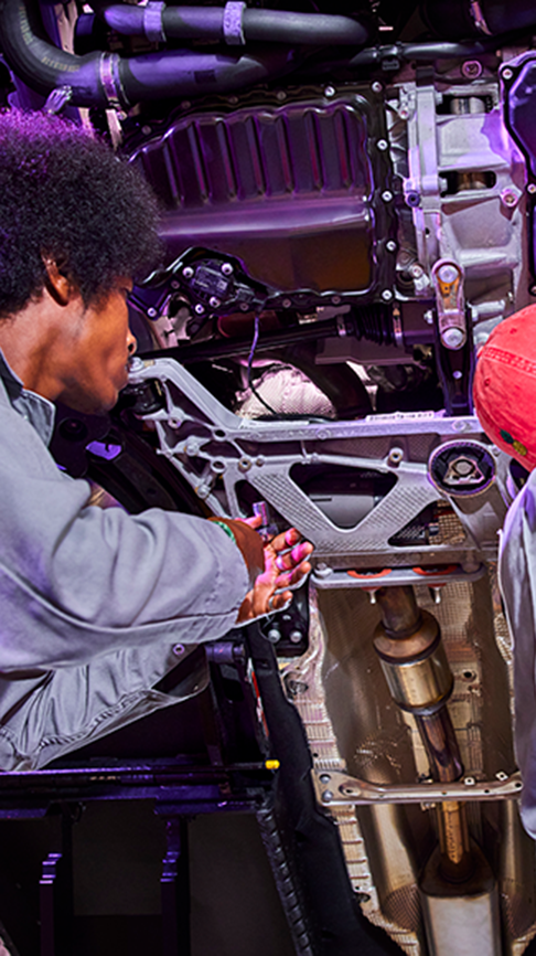 Two mechanics working on a car in a dealership service center