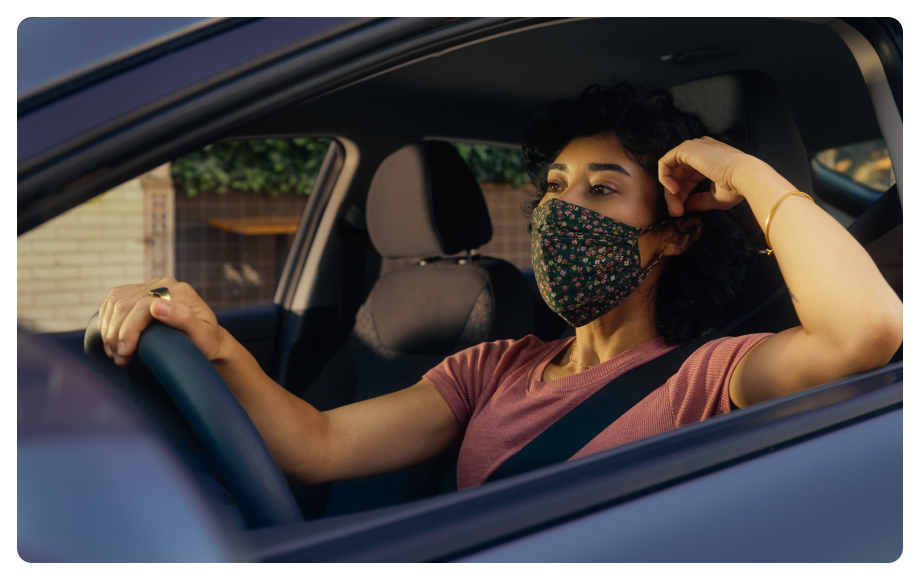 Woman Lyft driver driving her car wearing Covid mask to protect patient she is giving a ride