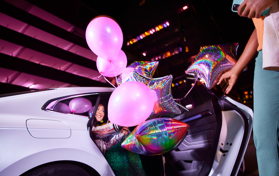 Woman dressed up for New Years celebration in her Lyft ride with a disco ball seatbelted next to her