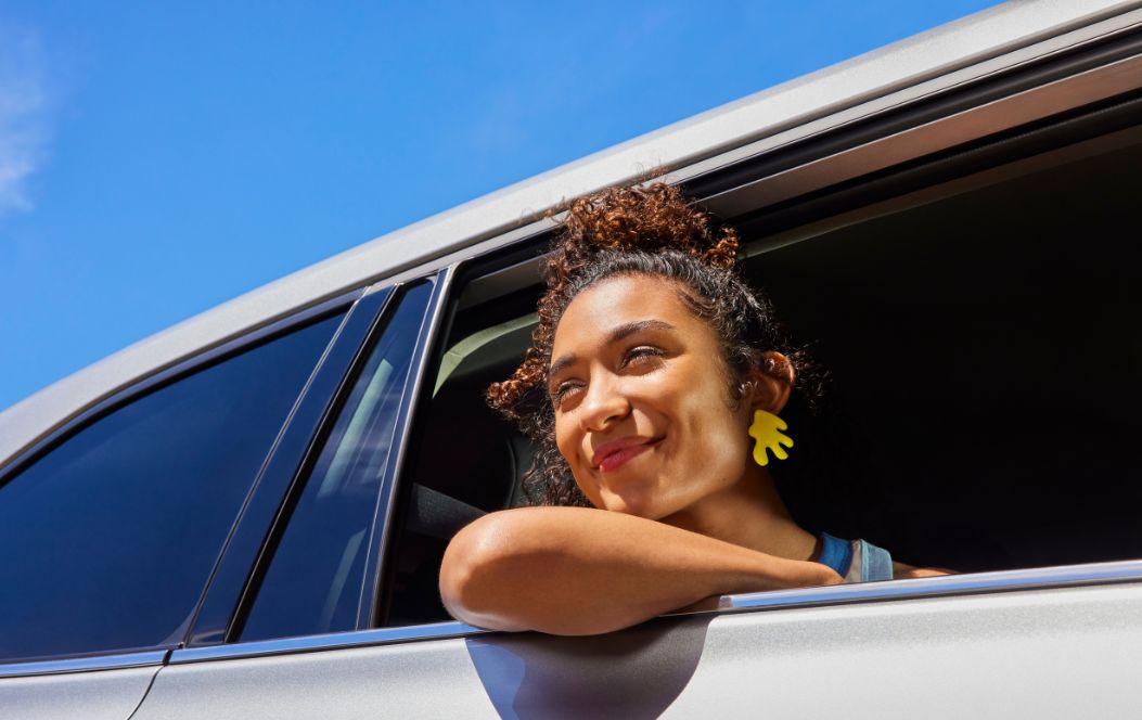 Woman smiling looking out of a car with the window rolled down