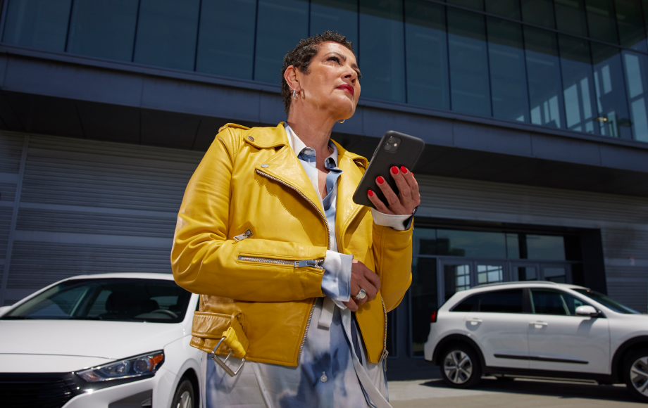 Woman at a car dealership holding her phone