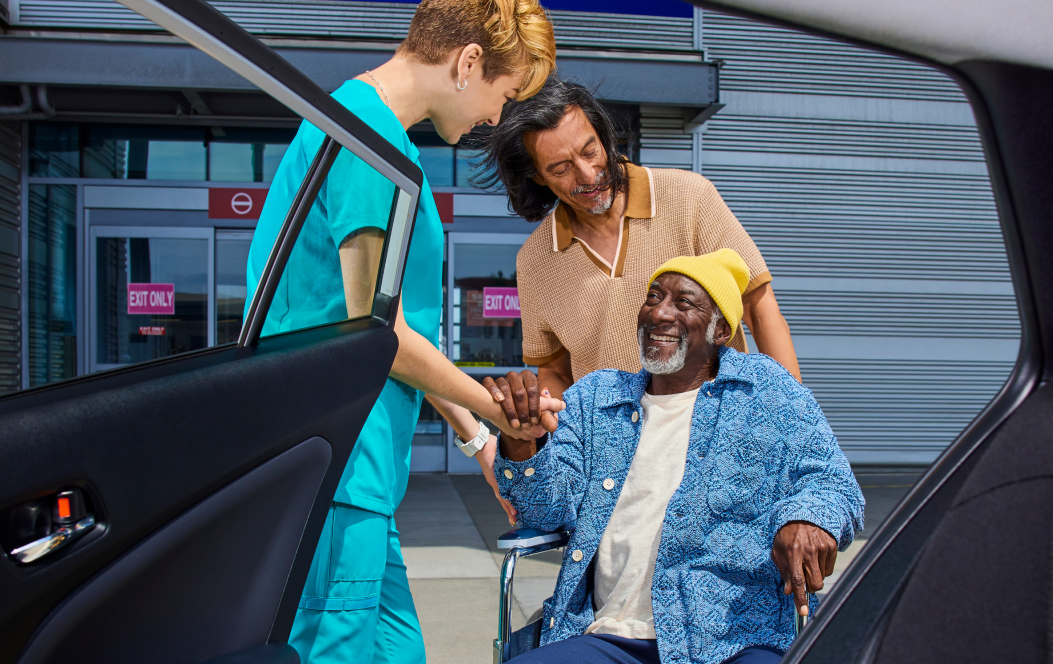 Nurse helping a man in a wheelchair get in a Lyft ride