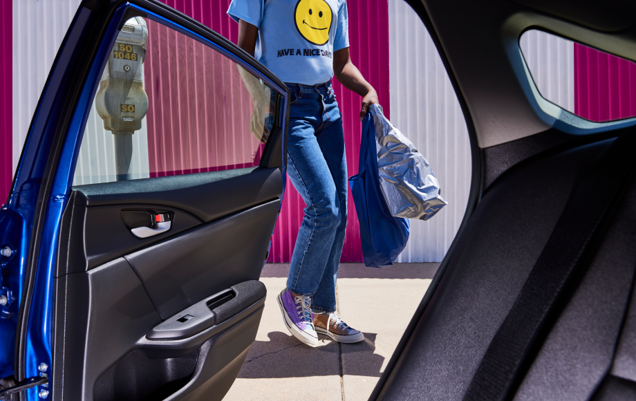Individual holding shopping bags getting into a Lyft ride.